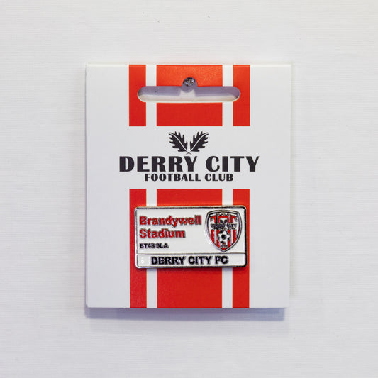 A Derry City Football Club enamel pin mounted on its original white display card, featuring red and white stripes and the club's name.